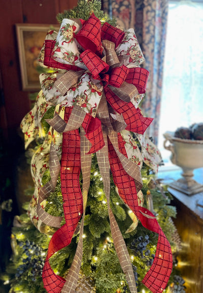 May include: Christmas tree topper bow in red and beige plaid ribbon. The bow features a burlap-like texture and glittery accents.  The ribbons are arranged in a cascading style, creating a lush and festive look. The design incorporates a cream-colored ribbon with a vintage-style Christmas print. This decorative tree topper is perfect for adding a touch of rustic elegance to any Christmas tree.
