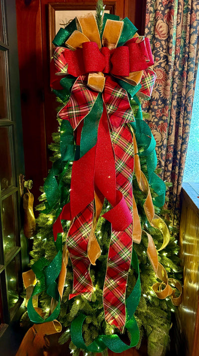 May include: A large Christmas tree topper bow featuring layered ribbons in red, emerald green, and gold. The design includes glittery red fabric, solid green glitter ribbon, and a red, green, and white plaid pattern with long, cascading tails.